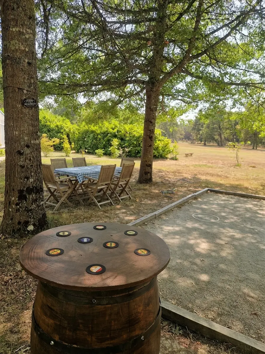 A pétanque court and wooden barrel table set beneath the trees