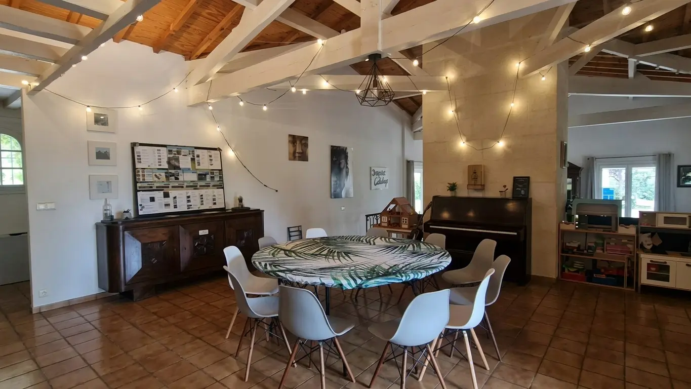 The cathedral-beamed lounge with a dining table, piano and festoon lights